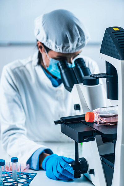 Scientist analyzing cultured artificial meat sample under the microscope in laboratory