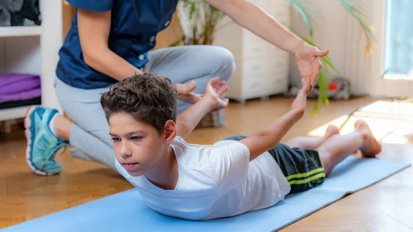 Lower back stretch. Boy exercising with physical therapist.