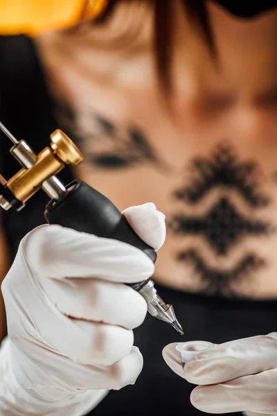 Kobieta Tatuażystka Przygotowuje Maszynę Tatuażu Ramieniu Mężczyzny — Zdjęcie stockowe