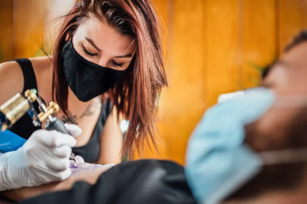 Tatuaż Bezpieczeństwa Podczas Kryzysu Koronawirusowego Tatuażysta Tatuujący Klienta Rękawiczkami Maską — Zdjęcie stockowe