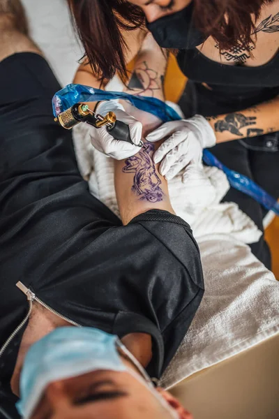 女纹身大师纹身男子手臂在工作室的头像 — 图库照片