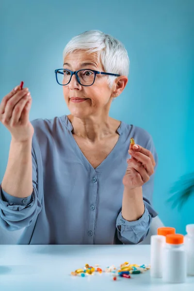 Confused Senior Woman Looking Her Medicines Table Medicine Non Adherence —  Fotos de Stock