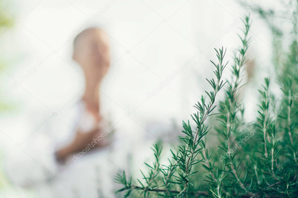 Manifesting Abundance Concept.. Middle Age Woman Expressing Positivity, Dressed in White, enjoying the scent of Rosemary.