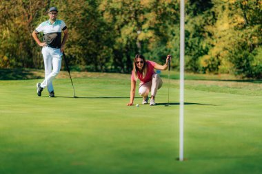 Golf oynayan, yeşili okuyan bir kadın.