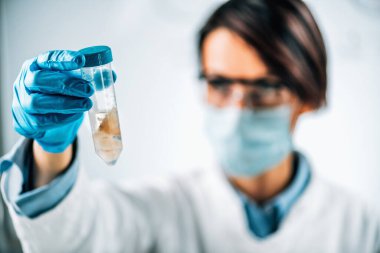 Deniz balıklarının Gıda Kalite Kontrolü - Duyusal Değerlendirme. Kalite kontrol uzmanı balık örneğiyle birlikte test tüpü tutuyor..