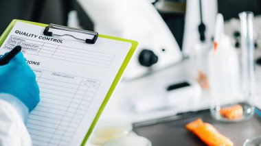 Gıda güvenliği ve kalite yönetimi. Gıda güvenliği ve kalite kontrol müfettişi laboratuarda kalite kontrol formu dolduruyor, arka planda somon balığı var.