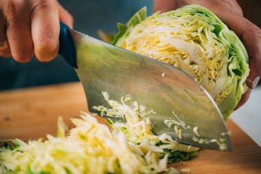 Fermentation process. Woman preparing vegetables for fermentation at home. Cutting cabbage.