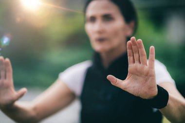 Qi Gong. Mature woman practicing Qi Gong in a park. Focus on womans hands. 