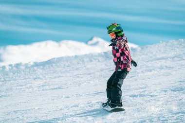 Child Snowboarding in the Mountains