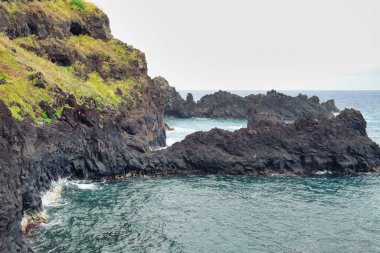 Okyanusun berrak sularıyla dolu küçük bir tatil beldesi olan Porto Moniz, Madeira 'daki deniz suyu doğal lav havuzları lezzetli bir yüzme ya da kürek çekme olanağı sunar..