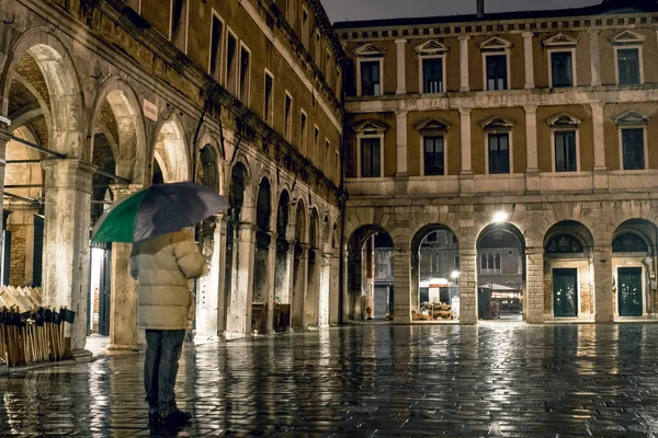 A lonely person dreaming on the old square of Venice, Italy, on rainy evening