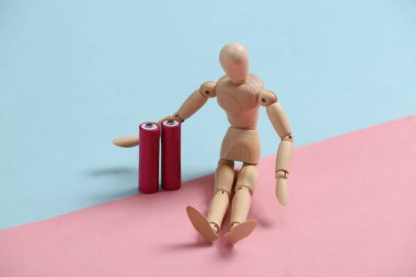 Pembe arka planda pilleri olan tahta bir kukla oturuyor.