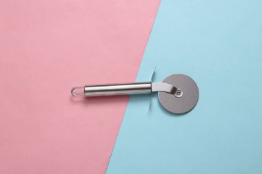 Pembe arka planda pizza kesmek için çelik yuvarlak bıçak.