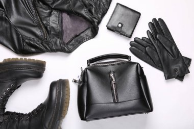 Kadın deri giysileri, ayakkabıları ve aksesuarlarının düz kompozisyonu. Ceket, bot, çanta, çanta ve eldivenler beyaz arka planda. Üst görünüm