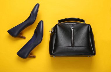 Topuklu deri ayakkabılar ve sarı arka planda bir el çantası. Kadın aksesuarları. Üst görünüm