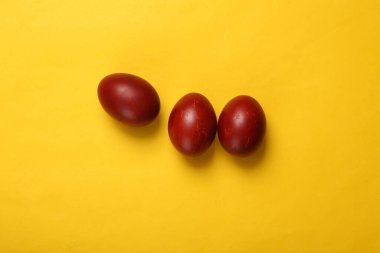 Sarı arka planda kırmızı paskalya yumurtaları boyadım. Paskalya minimalist kompozisyonu. Üst görünüm