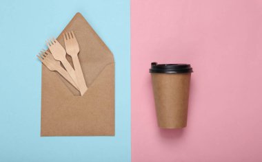 Eko konsepti. Üzerinde kahve fincanı ve ahşap çatallar olan mavi pastel arka planda bir zarf.