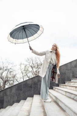 Merdivenlerde şemsiyesi olan şık bir kız.
