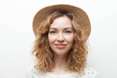 Beyaz arka planda saman şapkalı, sevimli, kıvırcık saçlı beyaz kadın portresi.