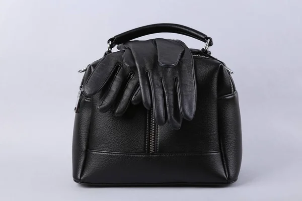 グレーの背景にスタイリッシュな黒革の手袋とハンドバッグ — ストック写真