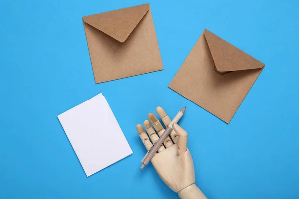 Holzhand Schreibt Einen Brief Auf Blauem Hintergrund — Stockfoto
