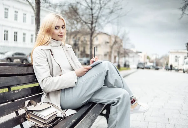 Stilvolle Junge Frau Sitzt Auf Einer Bank Und Schreibt Notizbuch — Stockfoto
