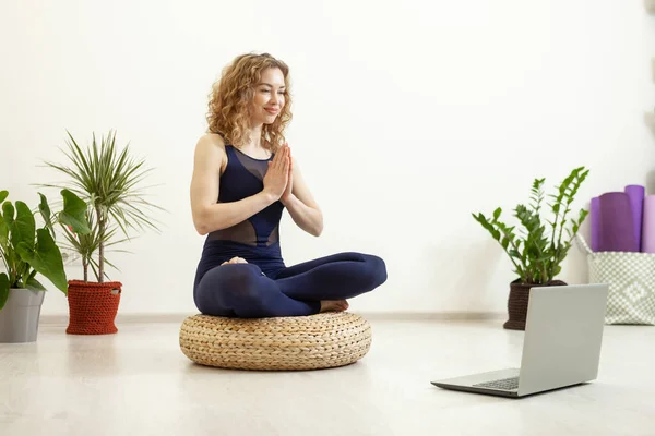 Yoga woman doing online lesson with laptop in living room. Lifestyle.