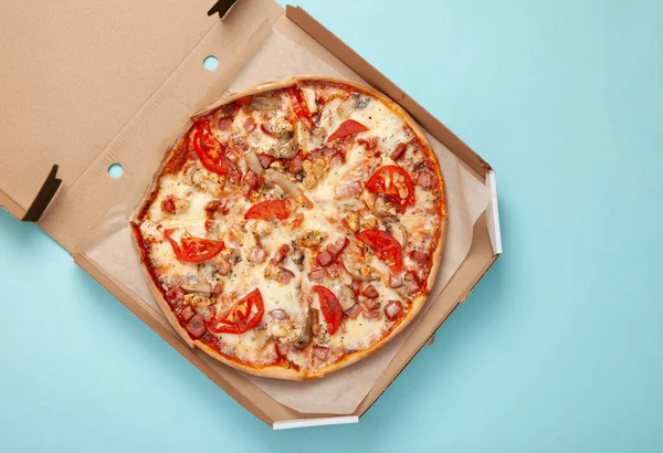 Pizza in an open box on blue background. Top view