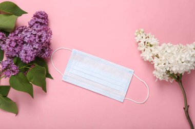 Pembe arka planda çiçek açan leylak dalları olan tıbbi maske