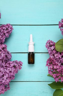 Mavi arka planda çiçek açan leylak dallarıyla burun spreyi.