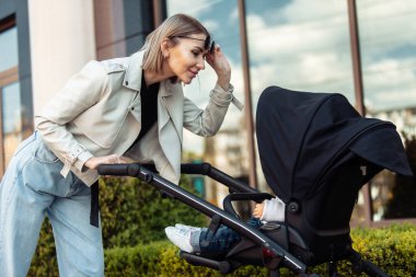 Şık, sevgi dolu bir anne şehir merkezinde bir bebek arabasıyla yürüyor. Annelik, yaşam tarzı