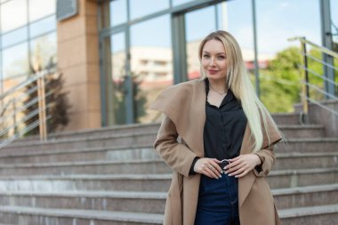 Trençkotlu şık bir iş kadını merdivenlerden iniyor.