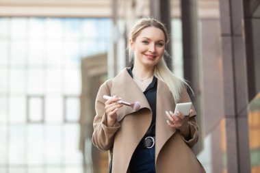 Güzel sarışın kadın şehirde fırçayla makyaj yapıyor.