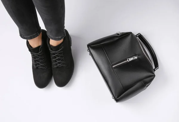 穿着靴子的女人的腿和白色背景的黑色皮包 时尚的概念 顶部视图 — 图库照片