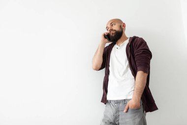 Beyaz arka planda telefonla konuşan kel, yakışıklı bir adam.