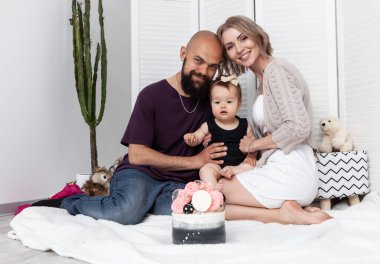 Mutlu aile kavramı. Anne ve küçük kızını önemseyen baba doğum günlerini pastayla kutluyorlar. Sevgi ve ilgi. Çocukluk. Tatil