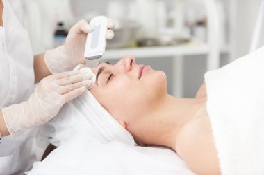 Güzel bir kadın ultrasonik kabuk soyma ameliyatı oluyor. Ultrasonik deri temizleme prosedürü. Kozmetik prosedürleri. Kozmetoloji. Güzellik salonu. Cilt bakımı.
