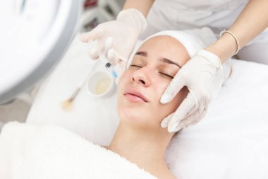 Kozmetik uzmanı, güzel bir kadının dudak büyütme ve kırışıklık önleyici iğneleri yapar. Güzellik salonunda kadın kozmetolojisi.