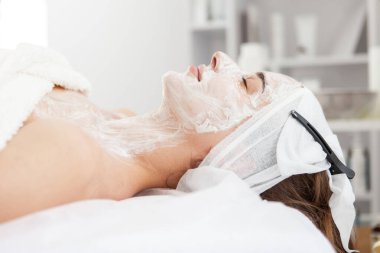 Cilt bakımı. Gençleştirici maskeli güzel bir kadın. Güzellik salonunda gözleri kapalı.