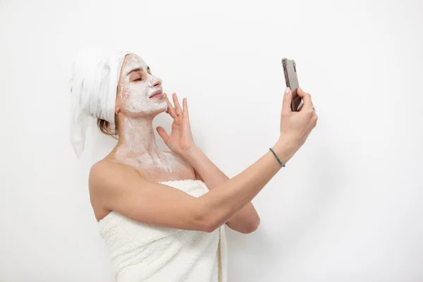 Όμορφη Γυναίκα Μάσκα Προσώπου Κοιτάζει Την Οθόνη Του Smartphone Λευκό — Φωτογραφία Αρχείου