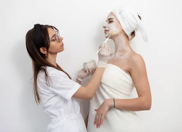Lekarz Kosmetolog Nakłada Maskę Twarzy Pędzlem Młodą Piękną Klientkę Białym — Zdjęcie stockowe