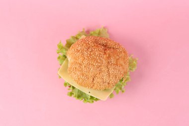 Pembe arka planda iştah açıcı bir burger. Üst görünüm