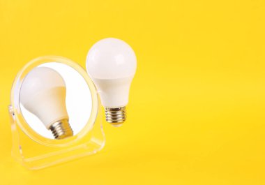 Sarı arka planda ayna olan uçan ampul. Asgari, fikir kavramı