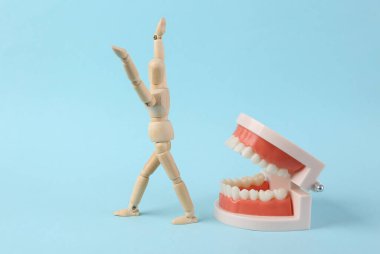 Mavi arka planda korkmuş tahta kuklaları olan insan çenesinin plastik modeli. Dişçilik korkusu