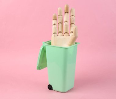 Ahşap el, pembe arka planda oyuncak çöp kutusunda.