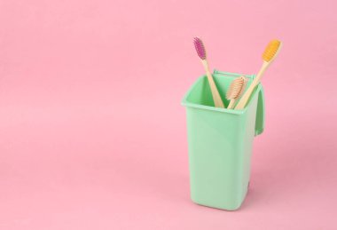 Pembe arka planda çöp tenekesinde eko bambu diş fırçaları