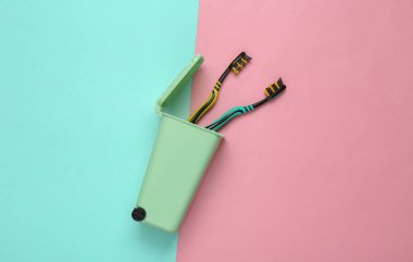Pembe arka planda mini çöp kutusunda plastik diş fırçaları. Plastiksiz. Geri dönüşüm konsepti. Üst Manzara. Düz yatıyordu