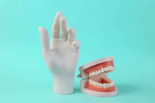 青い背景に白い歯と白い手を持つ人間の顎のモデル ミニマル コンセプト アート — ストック写真