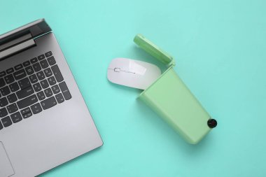 Oyuncak çöp kutusunda bilgisayar faresi ve pembe mavi arka planda dizüstü bilgisayar. Geri dönüşüm konsepti. Bilgi çöplüğü. Üst manzara, düz uzanma