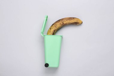 Gri arka planda mini çöp kutusunda çürük muzlar. Üst Manzara. Düz yatıyordu